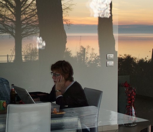 Fabienne travaille dans lle décor surréaliste de notre salle à manger noyée dans le reflet du coucher de soleil.